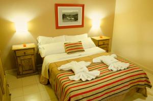1 dormitorio con 1 cama con toallas en Complejo el Paine en Villa General Belgrano