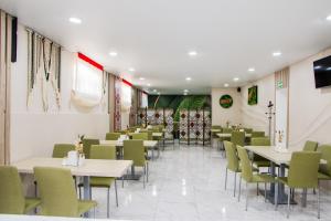 a restaurant with white tables and green chairs at Гостинний двір "Марія" in Kropyvnytskyi