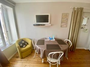 a dining room with a table and chairs and a tv at Le Petit Logis - Vue Mer in Granville