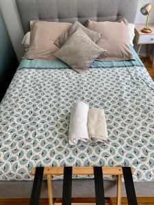 a bed with two pillows and two towels on it at Le Petit Logis - Vue Mer in Granville