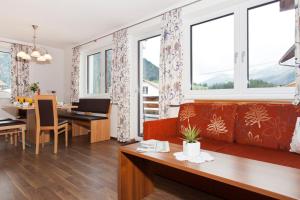 Ferienhaus Luis في ناودرس: غرفة معيشة مع أريكة حمراء وغرفة طعام