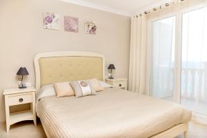 a white bedroom with a bed with two tables and a window at Aparthotel Ola Blanca in Cala de Finestrat