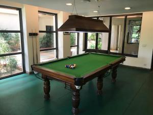 una mesa de billar verde en una habitación con ventanas en Premium Apartment in Tarudhan Valley Golf Resort, en Manesar