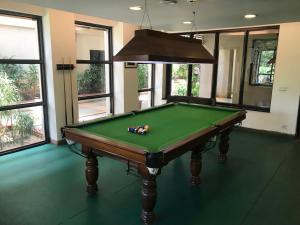 a green pool table in a room with windows at Premium Apartment in Tarudhan Valley Golf Resort in Manesar