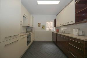 a large kitchen with white appliances and wooden cabinets at Town centre 4xbed 4xbath apartment in Elgin