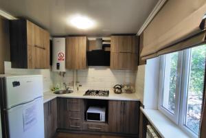 a small kitchen with wooden cabinets and a white refrigerator at Двухкомнатный люкс центр Соборности 29 KR Apartments in Kryvyi Rih +13 photos