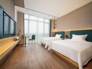 a hotel room with two beds and a flat screen tv at Chaoman Hotel in Jingzhou