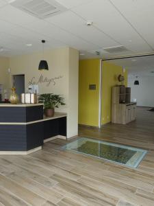 vestíbulo con paredes amarillas y suelo de cristal en Hôtel - Restaurant Le MITIGANA, en Migennes