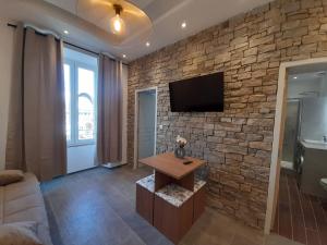 a living room with a stone wall and a tv at BRILOC AJACCIO centre ville in Ajaccio