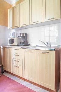 a kitchen with wooden cabinets and a sink and a microwave at AL-DOM apartamenty Róża 101 in Kołobrzeg