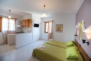 a bedroom with a green bed and a kitchen at Ilios Studios in Lefkada