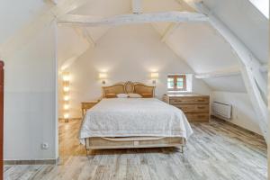 a white bedroom with a bed and a wooden floor at Harmonia - maison de caractère proche Provins in Gouaix