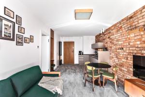 ein Wohnzimmer mit einem grünen Sofa und einer Ziegelwand in der Unterkunft Apartament Pionier41 in Stettin