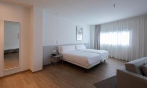 a bedroom with a white bed and a window at Apartamentos Forum Ceao in Lugo