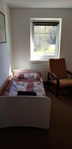 a bedroom with a bed and a chair and a window at Penzion CERNY MLYN SOKOLOV in Březová