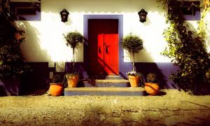 a red door with potted plants in front of a house at Lodge Monte Do Sobral in Alcáçovas