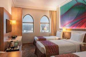 a hotel room with two beds and two windows at Al Madina Golden Hotel in Al Madinah