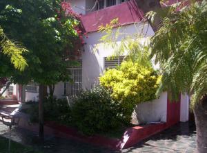 un edificio blanco con árboles y arbustos delante de él en El Mirador de Tandil en Tandil