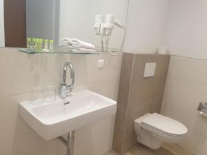 a white bathroom with a sink and a toilet at Hotel Garni Wurzer in Velden am Wörthersee +37 photos