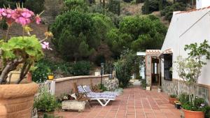 a patio with benches and plants and a fence at Casa rural Cristina- Piscina climatizada in Málaga