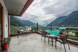 a balcony with tables and chairs and a view of mountains at Snow Bloom Resort in Manāli