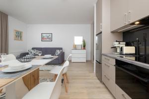 a kitchen with a table and white chairs in a room at Apartament Holiday B 101 in Pobierowo