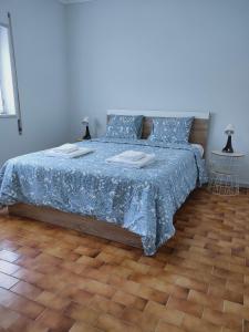 a bedroom with a bed with blue sheets and a wooden floor at Residencias Ana Carmen in Viana do Castelo