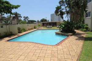a large swimming pool in a yard with a brick patio at SEALODGE 23 UMHLANGA BEACHFRONT in Durban