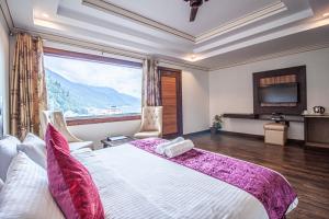 a bedroom with a large bed with a large window at Snow Bloom Resort in Manāli