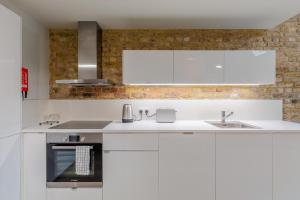a kitchen with white cabinets and a sink at StayInn Holborn in London