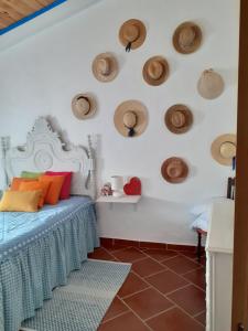 1 dormitorio con 1 cama con sombreros en la pared en Casa do Montinho, en Avis