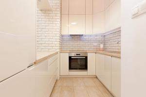 - une cuisine blanche avec des placards blancs et une cuisinière dans l'établissement Espace Wilanów Apartments by Renters, à Varsovie
