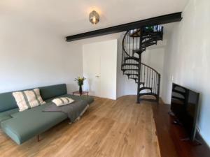 sala de estar con sofá verde y escalera de caracol en Sommerfrische Uckermark, en Warnitz