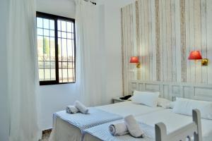 2 camas en una habitación blanca con ventana en Hotel Marisa, en Córdoba