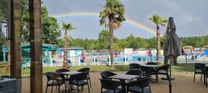 a rainbow over a swimming pool with tables and chairs at Mobilhome 2 ch,1 salon 40m2 de Charme dans camping *** in Saint-Julien-en-Born