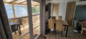 ein Esszimmer mit einem Tisch und einem Balkon in der Unterkunft Mobilhome 2 ch,1 salon 40m2 de Charme dans camping *** in Saint-Julien-en-Born