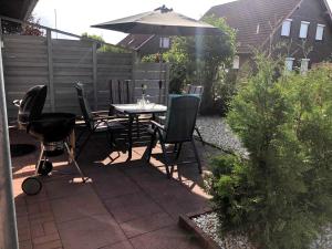 une terrasse avec une table, des chaises et un parasol dans l'établissement Ferienhaus Kristina, à Hooksiel