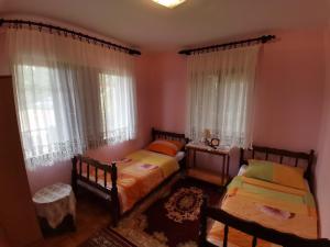two beds in a room with two windows at Apartman Jaredić - Private Accommodation, Privatni Smeštaj in Donji Milanovac