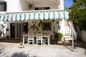 a patio with a table and chairs under a striped umbrella at Ostuni home nature in Ostuni
