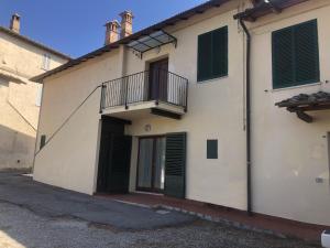 a white building with green shutters and a balcony at Le Castellacce in Siena