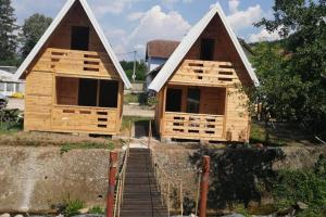 Dos casas se están construyendo sobre una pared. en Kamp Bungalovi Sase drvena kuca, en Višegrad