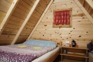 a bedroom with a bed in a wooden attic at Kamp Bungalovi Sase drvena kuca in Višegrad