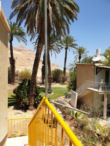 ein gelbes Geländer vor einem Haus mit Palmen in der Unterkunft הצימר של יהושע in Ein Gedi