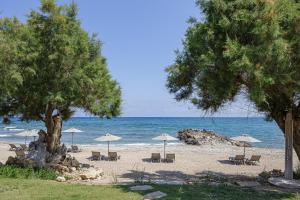 a beach with chairs and umbrellas and the ocean at Eleven Boutique Suites in Stavromenos +61 photos