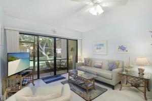 un salon avec un canapé et une télévision dans l'établissement Relaxing condo with two pools and steps to beach, à Marco Island