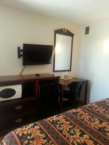 a bedroom with a bed and a desk with a mirror at Budget Inn in Fort Stockton