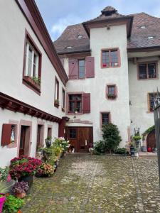 una grande casa bianca con un cortile di ciottoli di L'oriel des ménétriers de Ribeauvillé a Ribeauvillé