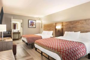 um quarto de hotel com duas camas e uma televisão em Days Inn & Suites by Wyndham Bowling Green em Bowling Green