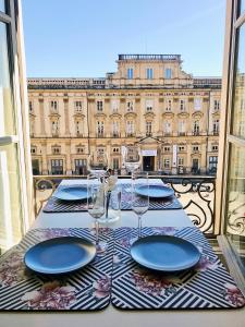 einen Tisch mit Tellern und Weingläsern auf dem Balkon in der Unterkunft Host inn Lyon - Appartement de Luxe aux Terreaux & Jacuzzi in Lyon