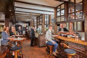a group of people sitting at a bar in a restaurant at Landhotel Naafs-Häuschen in Lohmar
